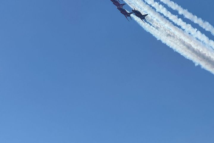 Nine jets flying in formation, trailing white smoke against a clear blue sky.