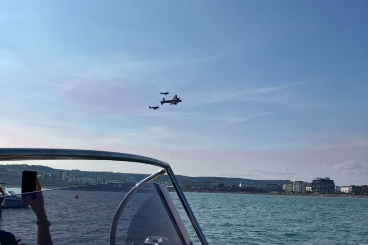 Person on a boat photographing three planes flying over a coastal town.