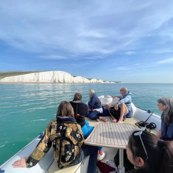 a group of people sitting next to a body of water