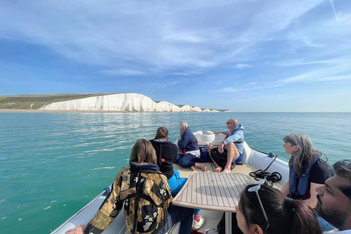 a group of people sitting next to a body of water