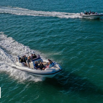 a man riding on the back of a boat in the water