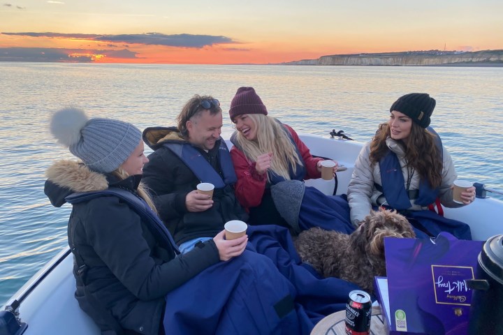 a group of people sitting next to a body of water