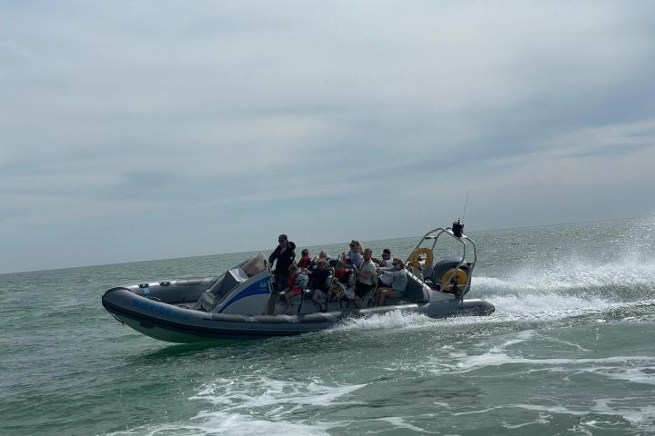 a group of people riding on the back of a boat in the water