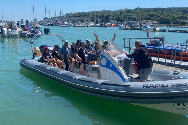 Group of people on a motorboat in a marina with clear skies.