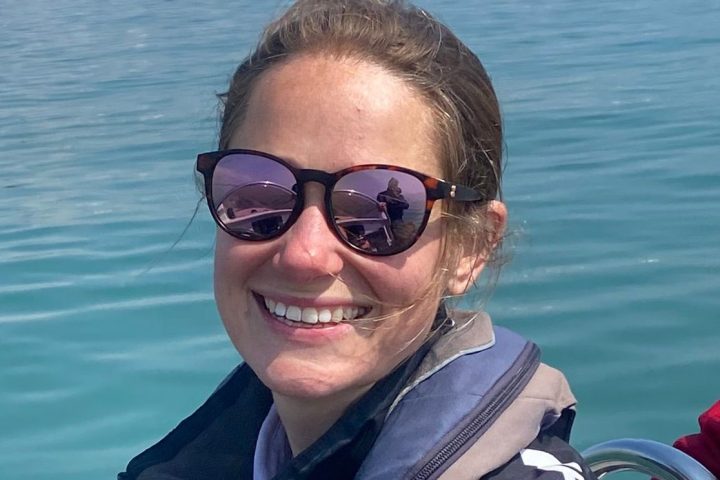 a man wearing sunglasses and sitting in a boat on a body of water