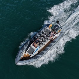 Aerial view of a speedboat with people moving swiftly on water.