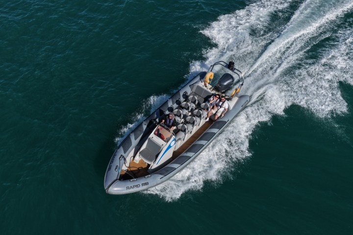 Aerial view of a speedboat with people moving swiftly on water.