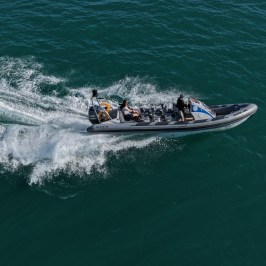 Boat speeding on blue water with waves trailing behind.