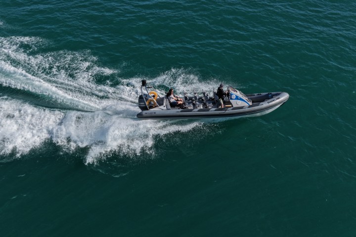 Boat speeding on blue water with waves trailing behind.